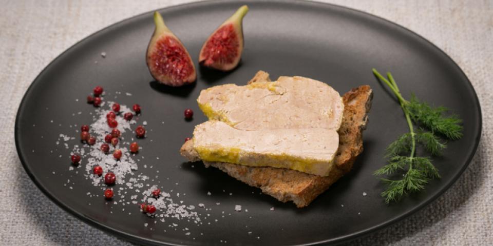 Photo d'une tranche de foie gras sur du pain grillé dans une assiette noire et décorée